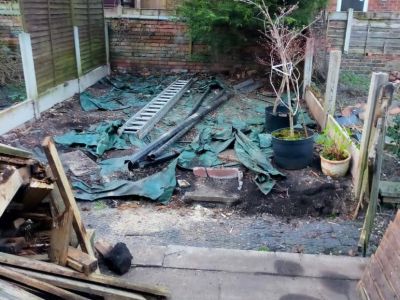 a disheveled backyard with tarps, a ladder, and debris scattered around. It appears to be in a state of disrepair or undergoing some kind of work.